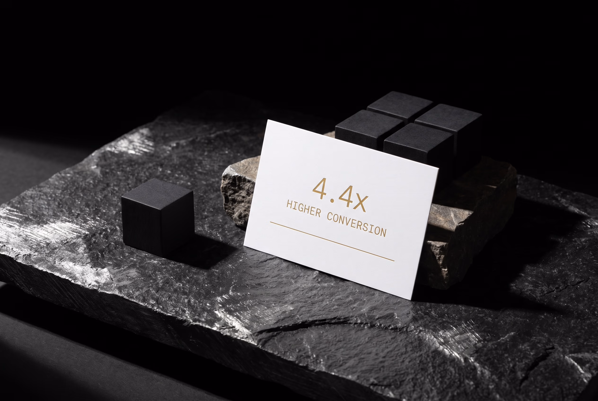 White 4.4 times higher conversion card arranged with black blocks on textured dark stone
